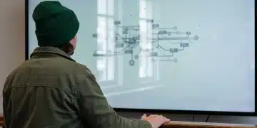Vue de dos d'une personne portant un bonnet vert et une veste, observant un écran affichant un réseau complexe de parcours clients omnicanaux, symbolisant l'intégration stratégique des canaux de vente.